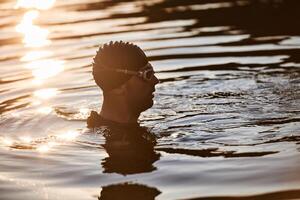 A triathlete finds serene rejuvenation in a lake, basking in the tranquility of the water after an intense training session photo