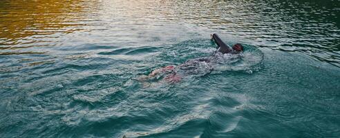 A professional triathlete trains with unwavering dedication for an upcoming competition at a lake, emanating a sense of athleticism and profound commitment to excellence. photo