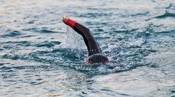 A professional triathlete trains with unwavering dedication for an upcoming competition at a lake, emanating a sense of athleticism and profound commitment to excellence. photo