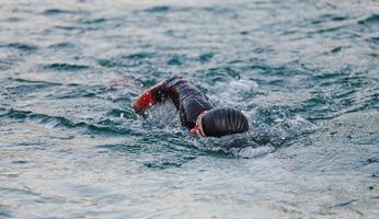 A professional triathlete trains with unwavering dedication for an upcoming competition at a lake, emanating a sense of athleticism and profound commitment to excellence. photo