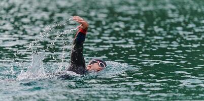 A professional triathlete trains with unwavering dedication for an upcoming competition at a lake, emanating a sense of athleticism and profound commitment to excellence. photo