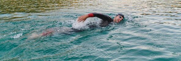 A professional triathlete trains with unwavering dedication for an upcoming competition at a lake, emanating a sense of athleticism and profound commitment to excellence. photo