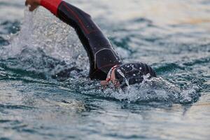 A professional triathlete trains with unwavering dedication for an upcoming competition at a lake, emanating a sense of athleticism and profound commitment to excellence. photo