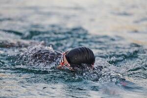 A professional triathlete trains with unwavering dedication for an upcoming competition at a lake, emanating a sense of athleticism and profound commitment to excellence. photo