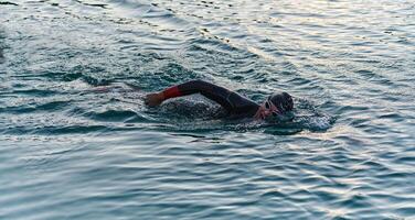A professional triathlete trains with unwavering dedication for an upcoming competition at a lake, emanating a sense of athleticism and profound commitment to excellence. photo