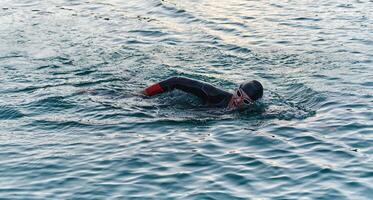 A professional triathlete trains with unwavering dedication for an upcoming competition at a lake, emanating a sense of athleticism and profound commitment to excellence. photo