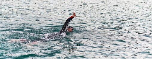 A professional triathlete trains with unwavering dedication for an upcoming competition at a lake, emanating a sense of athleticism and profound commitment to excellence. photo