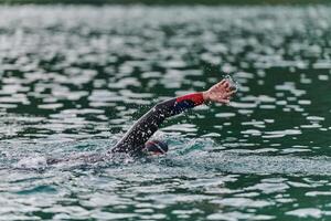 A professional triathlete trains with unwavering dedication for an upcoming competition at a lake, emanating a sense of athleticism and profound commitment to excellence. photo