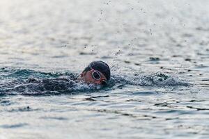A professional triathlete trains with unwavering dedication for an upcoming competition at a lake, emanating a sense of athleticism and profound commitment to excellence. photo