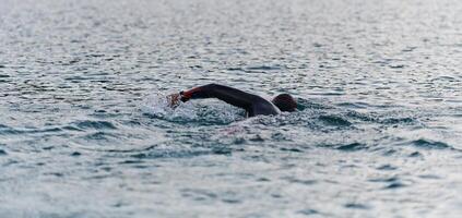 A professional triathlete trains with unwavering dedication for an upcoming competition at a lake, emanating a sense of athleticism and profound commitment to excellence. photo