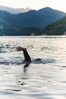 A professional triathlete trains with unwavering dedication for an upcoming competition at a lake, emanating a sense of athleticism and profound commitment to excellence. photo