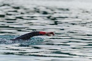 A professional triathlete trains with unwavering dedication for an upcoming competition at a lake, emanating a sense of athleticism and profound commitment to excellence. photo