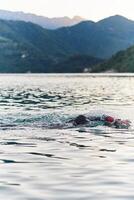 A professional triathlete trains with unwavering dedication for an upcoming competition at a lake, emanating a sense of athleticism and profound commitment to excellence. photo