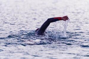 A professional triathlete trains with unwavering dedication for an upcoming competition at a lake, emanating a sense of athleticism and profound commitment to excellence. photo