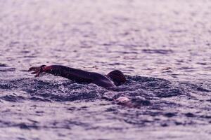 A professional triathlete trains with unwavering dedication for an upcoming competition at a lake, emanating a sense of athleticism and profound commitment to excellence. photo