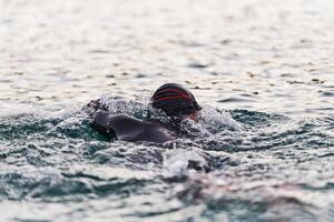 A professional triathlete trains with unwavering dedication for an upcoming competition at a lake, emanating a sense of athleticism and profound commitment to excellence. photo