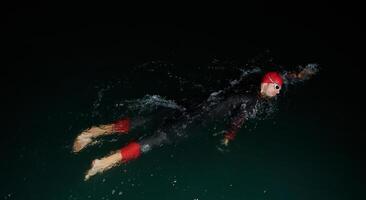 A determined professional triathlete undergoes rigorous night time training in cold waters, showcasing dedication and resilience in preparation for an upcoming triathlon swim competition photo