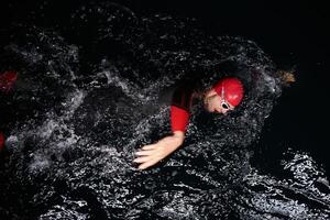 A determined professional triathlete undergoes rigorous night time training in cold waters, showcasing dedication and resilience in preparation for an upcoming triathlon swim competition photo