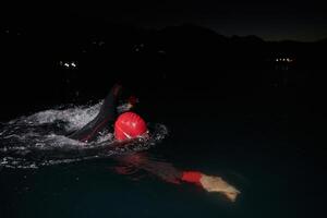 A determined professional triathlete undergoes rigorous night time training in cold waters, showcasing dedication and resilience in preparation for an upcoming triathlon swim competition photo
