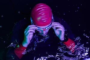 A determined professional triathlete undergoes rigorous night time training in cold waters, showcasing dedication and resilience in preparation for an upcoming triathlon swim competition photo