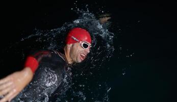 A determined professional triathlete undergoes rigorous night time training in cold waters, showcasing dedication and resilience in preparation for an upcoming triathlon swim competition photo