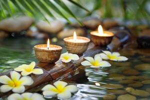 Three burning cosmetic candles on a bamboo stand, tropical flowers and leaves reflected in the water, sun bokeh, relaxation spa background photo