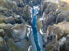 Drone shot of snowy icelandic canyon with frozen water stream and mountains covered in frost creating gorgeous scenery. Magical fjadrargljufur canyon with river in iceland, sightseeing. photo