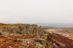 Steep highlands and river valley with rocks in Thingvellir national park, home to outstanding natural beauty. Breathtaking icelandic rocky hills and huge mountain walls, arctic scenery. photo