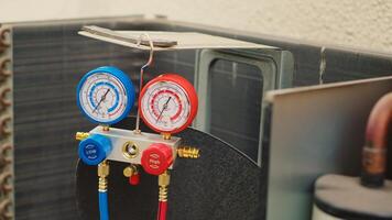 Zoom out shot of broken pressure measurement device used for checking hvac system freon pressure, in need of repair. Set of manifold meters showing high or low refrigerant levels photo