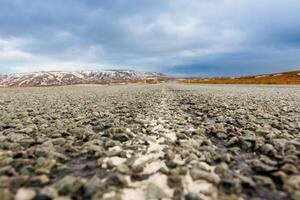 Icelandic landscape and long road in scandinavian scenery with empty roadside, frozen lands and fields in iceland. Spectacular panoramic view of arctic countryside, snowy mountains tops. photo