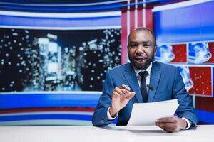 Talk show host addressing news on live transmission for global television program, using daily headlines to present important information and incidents. Presenter in studio doing reportage. photo