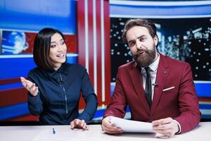 Diverse journalists reading daily headlines in studio, using media outlets papers to address latest information and updates about incidents. Presenters team reporting live for tv network. photo
