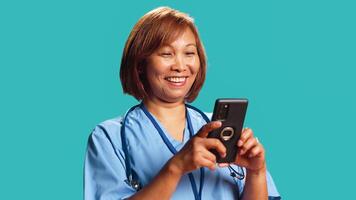 Jubilant nurse having burst of joy at work while chatting with friends, isolated over studio background. Elated hospital worker delighted about great news she received over the phone, close up photo