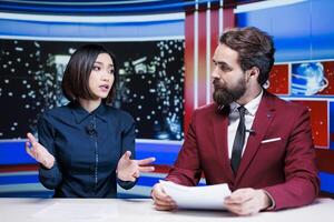 Diverse broadcasters reading daily headlines in newsroom, using media outlets papers to present latest information and updates about events. Journalists team reporting live for tv newscast. photo