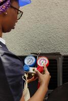 Capable specialist comissioned by customer to restore cooling capacity of air conditioner by inspecting system for leaks and recharging it with new refrigerant to prevent compressor issues photo