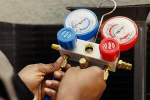 Pressure measurement device able to detect damaged expansion valve, freon not circulating properly and other issues. Close up of capable specialist using manifold meter to recondition hvac system photo