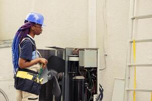 Technician ready to start work on air conditioner, commissioned to do for annual routine cleaning and maintenance removing built up layer of dirt and dust from internal parts using soft dusting brush photo
