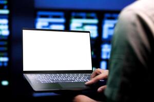 Skilled programmer conducting annual auditing of high tech facility servers using mock up laptop to optimize its lifespan, prevent downtime and ensure uninterrupted computing power photo
