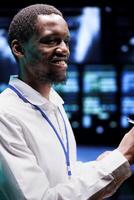 Cheerful engineer in data center using renewable energy sources to power crypto mining operations. Smiling expert working with eco friendly server racks preventing significant environmental impact photo
