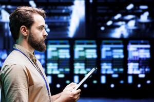IT developer setting up high tech data center firewalls, intrusion detection systems and doing security updates. Cybersecurity employee preventing hacking, malware, and DDoS attacks in server hub photo