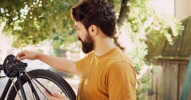Caucasian male cyclist using tablet to browse for equipment and gear to enhance yearly bike maintenance. Determined young man utilizing digital device looking for solutions of damaged bicycle. photo