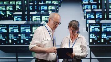 Cloud computing business executives looking around data center, using clipboard to crosscheck disaster recovery plan and assess high tech workplace servers in need of replacement, preventing concerns photo