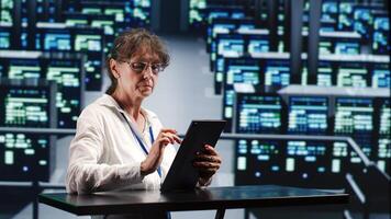 Precise serviceman in cloud computing company housing high end servers capable of quickly and efficiently performing complex computations and data analysis, using tablet to root out blips photo