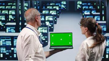 Experienced professionals looking around high tech data center, using mockup laptop to crosscheck disaster recovery plan and assess server infrastructure in need of replacement, preventing issues photo