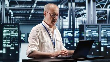 Certified technician expertly managing data while navigating in industrial server room. Professional ensuring optimal cybersecurity protection, optimizing systems and performing necessary updates photo