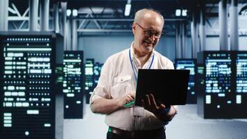 Capable serviceman expertly managing data while navigating in industrial server room. Proficient repairman in high tech facility ensuring optimal cybersecurity protection, optimizing systems photo