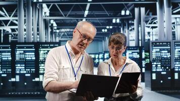 Elderly employees monitoring green energy data center infrastructure. Server systems using renewable sources employed to minimize consumption and reduce cloud computing business carbon footprint photo