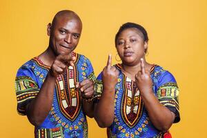 Black man and woman couple showing middle finger offensive gesture portrait. African american people showcasing provocative and rude behavior while looking at camera with negative expression photo