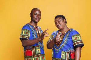 Smiling cheerful couple showing thumb up and ok symbol gesture portrait. Man and woman showcasing approval sign, giving positive feedback and looking at camera with carefree expression photo