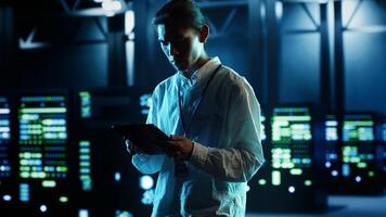 Asian man strolling through data center server rows providing processing and memory resources for different workloads. Engineer monitoring supercomputers tasked with solving complex operations photo
